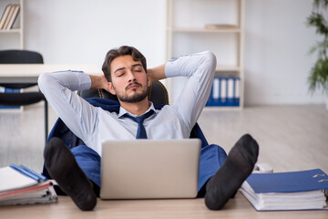 Young male employee extremely tired in the office