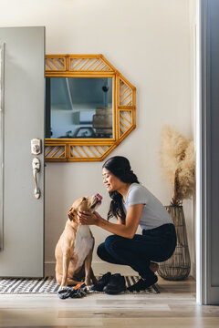 Woman With Pet Dog At Entrance Of Home
