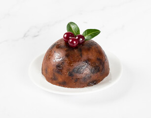 Traditional English pudding with dried fruits, nuts, honey, rum, decorated with cranberries on a plate on a white background