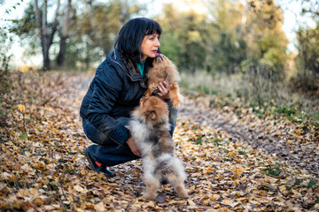 A woman walking with a pomeranian dog spitz in a park.