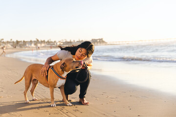 Woman Looking At Dog While Crouching On Shore