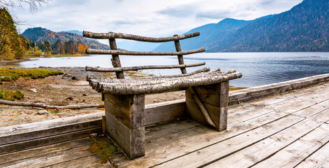 Wooden bench on a lake pier in the mountains. Beautiful place to relax in nature.