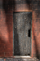 Burnt and charred wooden door and wall after a fire.
