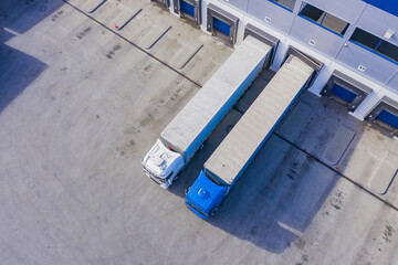 Aerial drone view on logistics center with trucks at the loading