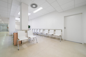 Chairs lined up in a hospital waiting room. Hospital interior with green floor without people.