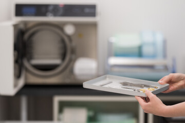 Sterilizing medical instruments in autoclave. Surgery office. Surgery assistant's hands get in sterilizing medical instruments to autoclave. Selective focus. Sterile surgery tools.