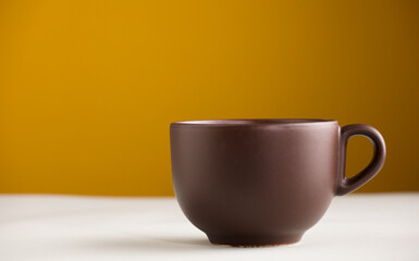 brown cup with coffee or chocolate, with yellow background