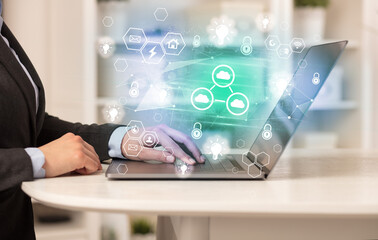 Hands working on laptop with digital icons