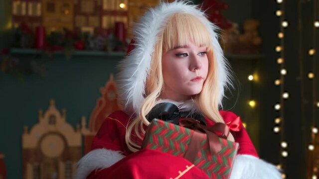 Cute little girl in a red costume of the New Year's elf. Posing for the photographer. New Year theme