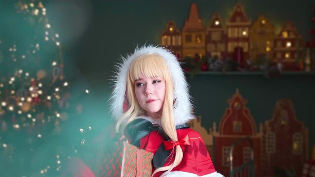 Cute little girl in a red costume of the New Year's elf. Blurred foreground. Camera movement to the side