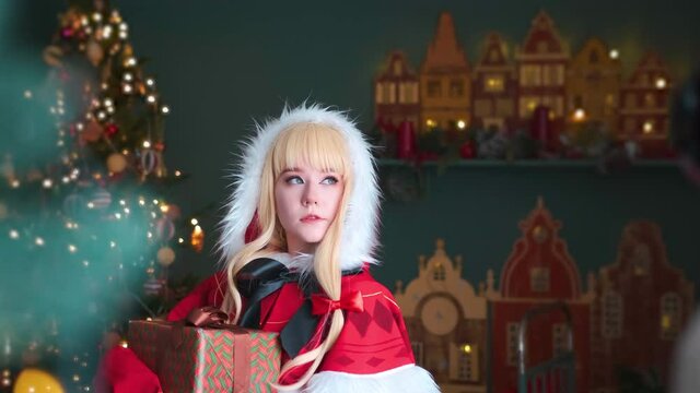 Cute little girl in a red costume of the New Year's elf. Posing for the photographer. New Year theme