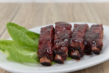 Barbecue ribs glazed with sauce and garnished with lettuce for you to eat