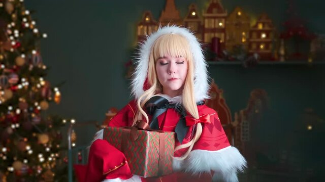 Red riding hood girl holding a gift in a red box. Beautiful eyes. Smiling