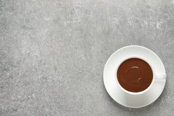 Yummy hot chocolate in cup on light grey table, top view. Space for text