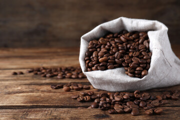 Bag of roasted coffee beans on wooden table, closeup. Space for text