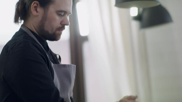 Portrait of a young handsome man chef at work. The cook prepares dought.