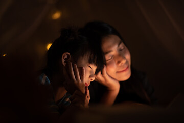 young Asian mother with little child daughter family happy in cozy night light at childhood home