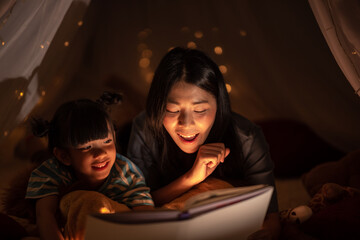 young Asian mother with little child daughter family happy in cozy night light at childhood home