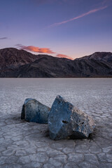 Two Sailing Stones Mimic The Distant Mountains At Sunset