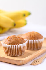 Homemade banana cupcake on wooden plate and banana fruit on white background