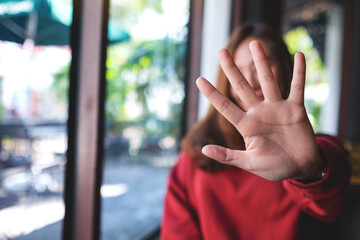 A young asian woman outstretched hand and showing stop hand sign