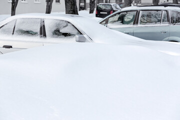 snow-covered cars on parking lot after winter blizzard in city