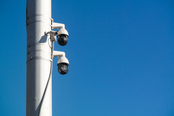 Modern cameras on a white pole against blue sky