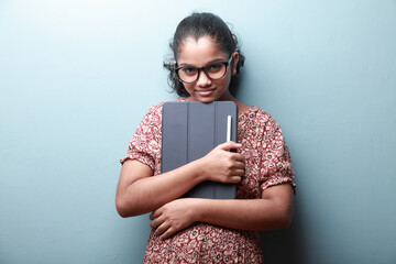 Portrait of a smiling girl of Indian ethnicity holding a tablet phone in hand
