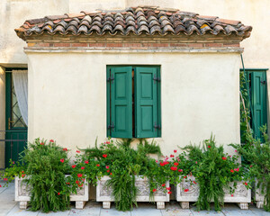 Fototapeta na wymiar Small seaside house with marble flowerpots full of rosemary and geraniums