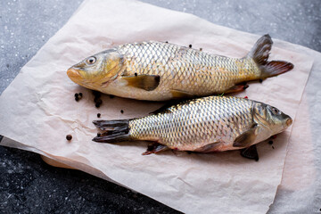 Fresh fish carp on paper, and black granite background