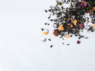 Black flavored tea with dry medicinal herbs scattered on the table top view. Soothing drink. Tea shop concept