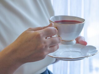 A woman in office clothes is holding a white cup of tea. Break, tea in the office. Light frame