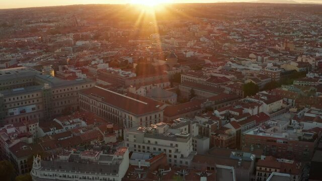 Aerial shot of buildings in town centre. Tilt up reveal cityscape and setting sun on horizon.