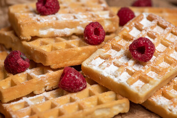 Bunch of waffles sprinkled with sugar and raspberries