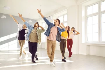 Deurstickers Group of happy young people enjoying a contemporary dance class. Cheerful, talented, beautiful male and female dancers in trendy casual wear dancing together in a modern, light, sunny dance studio © Studio Romantic