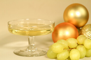 Glass of champagne next to bunch of grapes and Christmas decoration