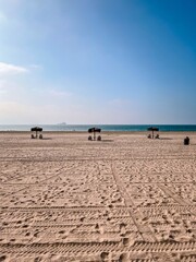 empty beach with palapas and ship in the background