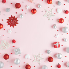 Beautiful round frame made of red, sliver and white christmas ornaments on pink background