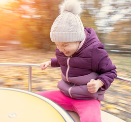 Young happy child merry go round outdoor in autumn