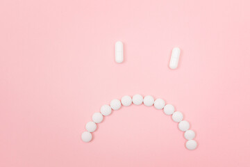 Pharma Harm. Sad Smiley Face Made from White Pills, Lying on Pink Backgrond. Global Pharmaceutical Industry and Medicinal Products