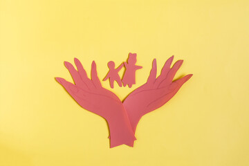 Obraz premium Cardboard figures hold small children with open palms of their hands. The concept of family and child protection
