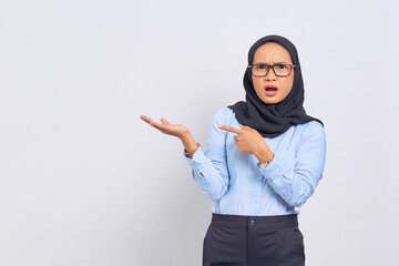 Portrait of shocked young Asian woman showing copy space on palm isolated on white background
