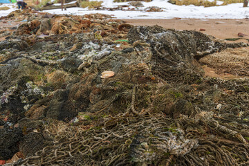 A pile of old fishing nets covered with snow on the sand. Teriberka village, Murmansk region, Russia.