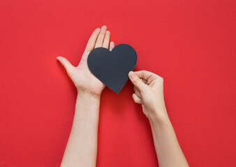 female hand holding heart on a red background. Concept of love, Charity and Relief Work. Valentines day. Copy space