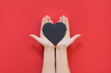 women's hands holding heart on a red background. Concept of love, Charity and Relief Work. Valentines day. Copy space