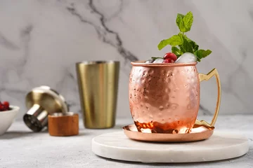 Foto op Plexiglas anti-reflex Traditional american alcoholic beverage moscow mule in copper mugs with cranberry and mint on white marble board - non-alcoholic cocktail version © Romana