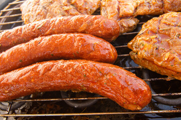 Pork steaks and sausages on a garden electric grill. Close-up.