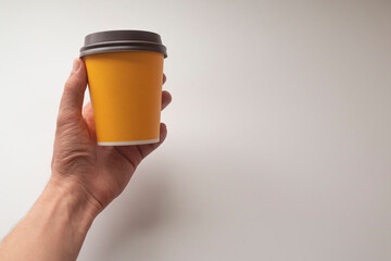 hand holding yellow coffee mug on white background.
mockup concept.
There is space for text and copy space.