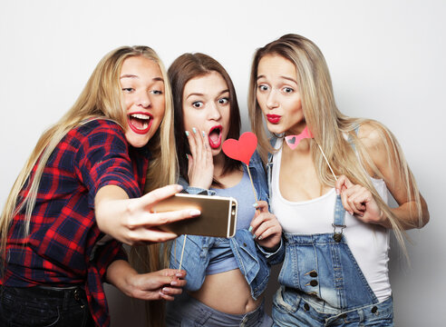 Happy young female friends taking some pictures with smartphone