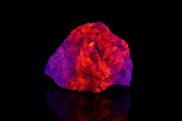 macro mineral stone Hackmanite under ultraviolet light on a black background